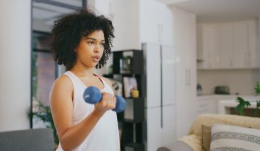 Shot of a young woman exercising with dumbbells at home